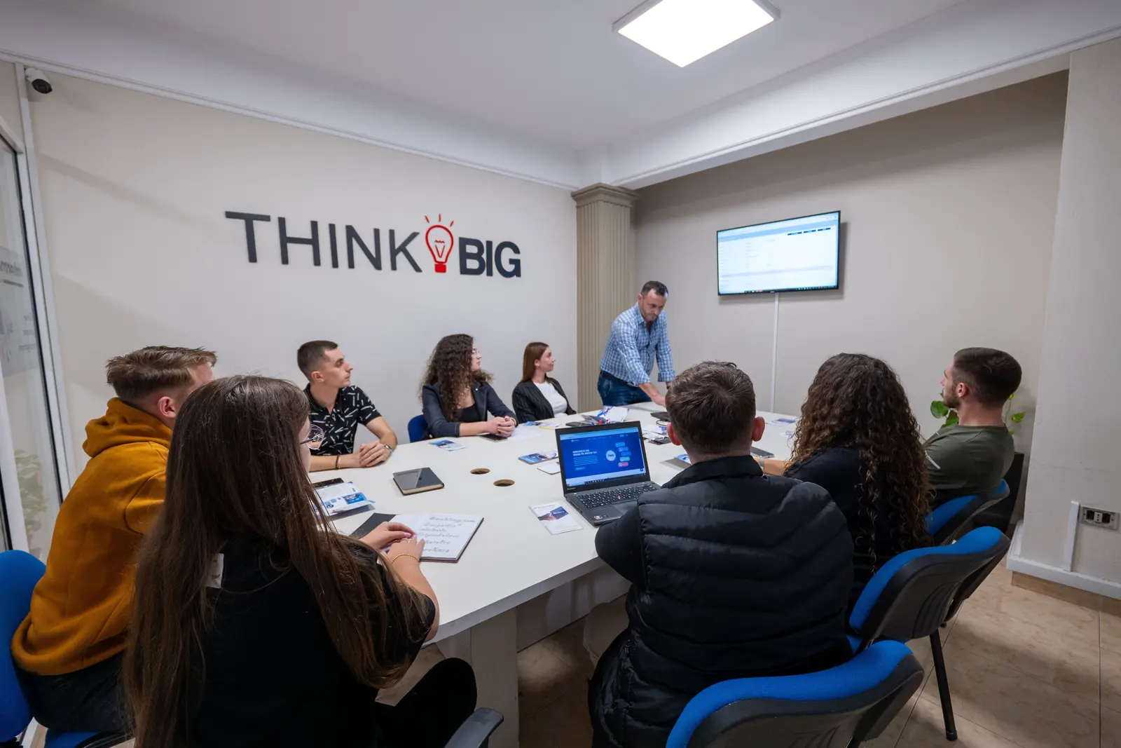 Ekipi i InterMedia në një mbledhje, në sallën me murin “Think Big”